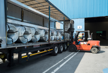 Trabajador de Celsa Group descargando acero en forma de hilo envuelto